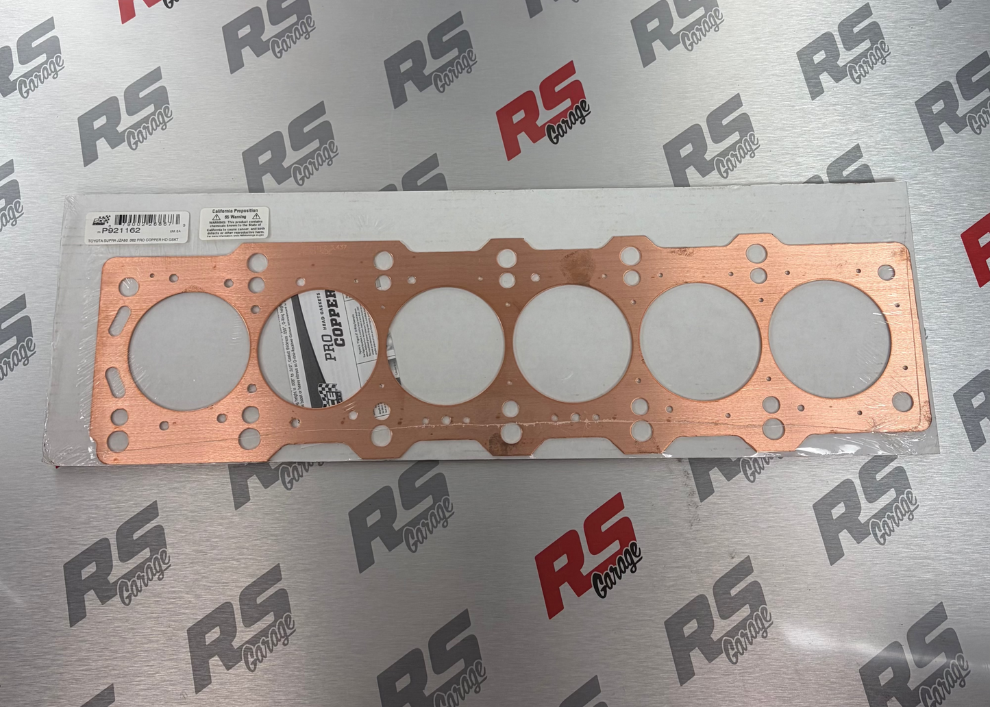 Copper gasket on a metallic surface with 'RS' branding.